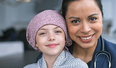 Female doctor with child cancer patient on her lap