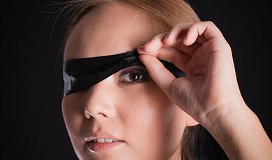 a ladys face with one eye covered with black tape
