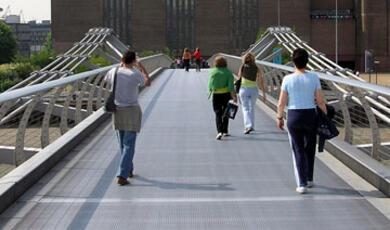 People walking across the Millennium Bridge in London