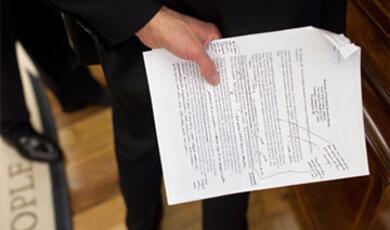A person's hands holding a document with text and signatures