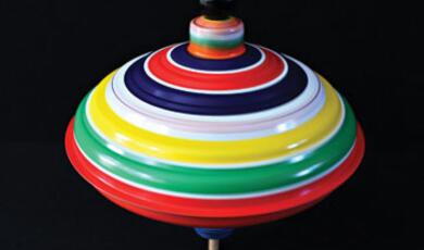 A colorful, multi-striped spinning top on a dark background
