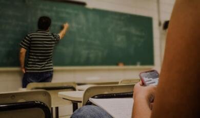 Man writing on a green chalkboard in classroom
