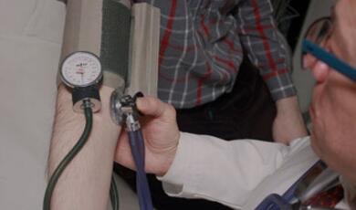 A healthcare professional measuring a person's blood pressure using a sphygmomanometer and a stethoscope