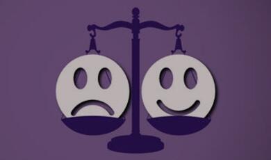Happy face and sad face each on either side of scales