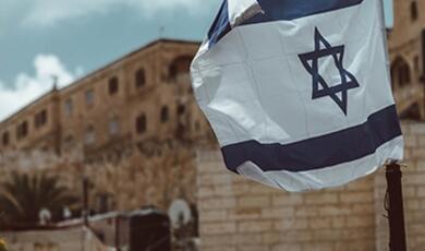 Israeli flag with buildings in background