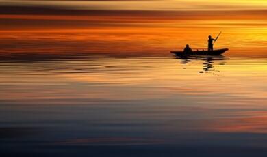 small boat silhouetted on the sea at sunset