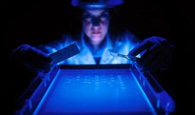 researcher holding pills, scalpel and looking at DNA