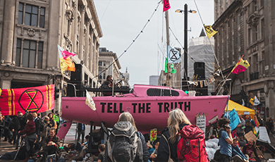 Pink boat with 'Tell the Truth' printed on the side, parked in the road at Oxford Circus as part of an Extinction Rebellion protest