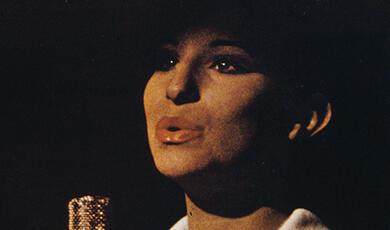 Photo of Barbra Streisand singing at microphone