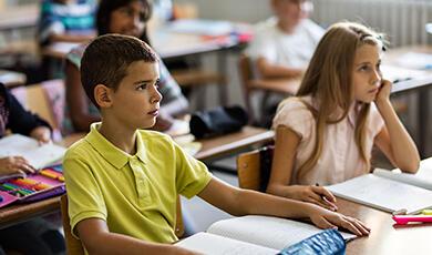 a boy and a girl sitting at desks in a classroom