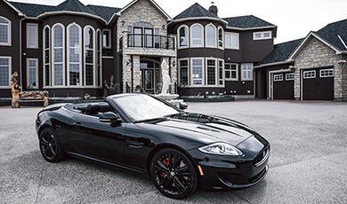Sports car in front of large house