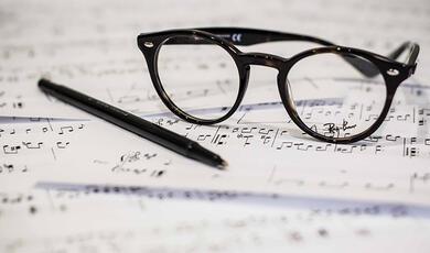 Glasses and pen set down of music manuscript