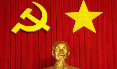 Red curtain with big, yellow, sickle and hammer and  star with bust of Lenin in foreground