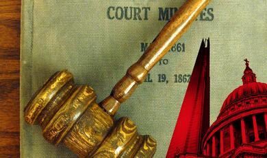 a judges gavel sitting on top of an old copy of court minutes
